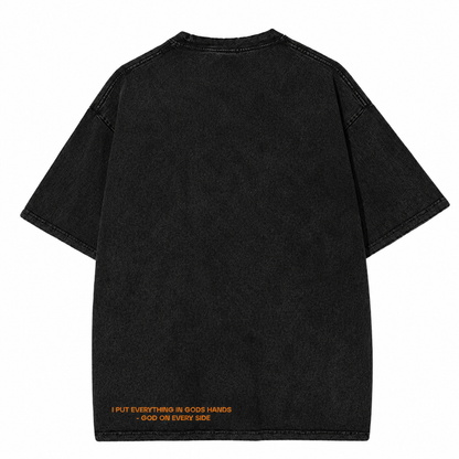 GOES Ascension Tee in acid-washed charcoal, featuring a subtle orange statement near the hem that reads, "I PUT EVERYTHING IN GOD'S HANDS – GOD ON EVERY SIDE.