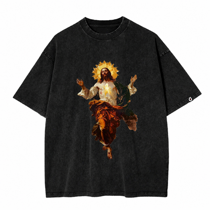 GOES Ascension Tee in acid-washed charcoal, featuring a bold front graphic of Jesus ascending with a radiant halo and glowing Sacred Heart. The back is finished with a subtle orange statement near the hem that reads, "I PUT EVERYTHING IN GOD'S HANDS – GOD ON EVERY SIDE.