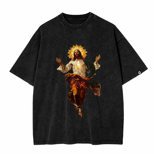 GOES Ascension Tee in acid-washed charcoal, featuring a bold front graphic of Jesus ascending with a radiant halo and glowing Sacred Heart. The back is finished with a subtle orange statement near the hem that reads, "I PUT EVERYTHING IN GOD'S HANDS – GOD ON EVERY SIDE.